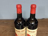 two bottles of wine sitting on a wooden table with a blue wall in the background