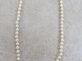 a close up of a pearl necklace with a gold clasp