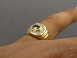 a woman ' s hand holding a gold ring with a blue stone