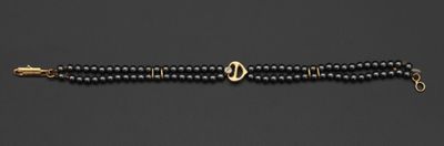 un bracelet en perles noires avec un fermoir doré sur fond noir
