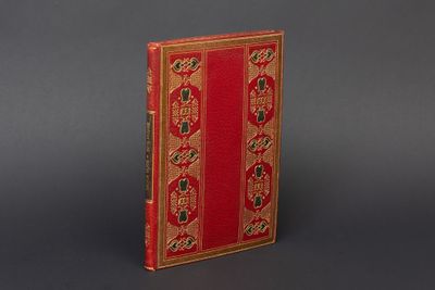 un vieux livre à la couverture rouge, rehaussée de dorures sur un fond gris
