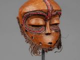 a close up of a wooden mask on a metal stand