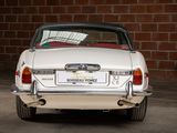 a white car parked in front of a brick wall