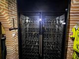 a wine cooler with many bottles in it in a room
