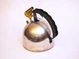 a silver kettle with a black handle on a white surface