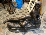 une statue en bronze représentant une femme allongée sur un lit