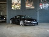 une Audi noire garée dans un parking à côté de deux vieilles voitures