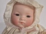 a baby doll that is wearing a bonnet and holding a teddy bear