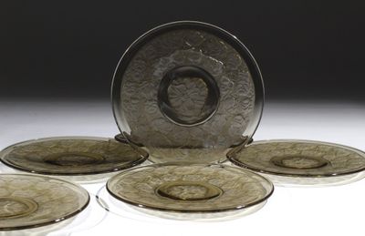 six assiettes en verre posées sur une table, surmontées d'une assiette en argent