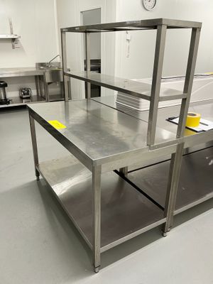 une cuisine avec des plans de travail en inox et une horloge accrochée au mur