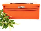 an orange purse sitting next to a plant on a white surface