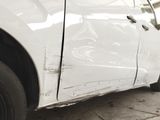 a white car that has been badly repaired and is sitting on the side of the road