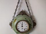 a clock hanging from a chain on the wall
