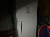 a white refrigerator in a dark room with a red and blue sign on it
