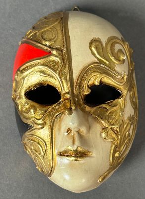 gold mask with red accents on a gray surface