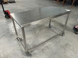 une table en acier inoxydable montée sur roulettes dans un entrepôt
