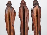 three wooden figurines of a man and a woman with a staff