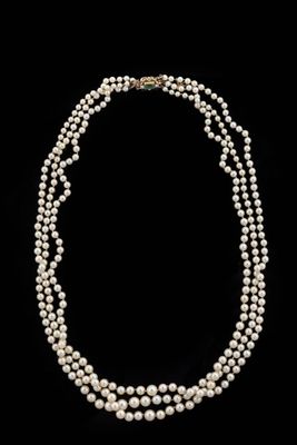 a three strand pearl necklace on a black background