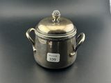 un petit pot en argent avec un couvercle, posé sur une table