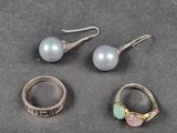 trois bagues et une paire de boucles d'oreilles sont posées sur une table