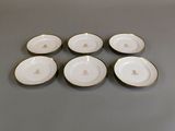 six assiettes blanches et dorées, avec des bords dorés sur un fond gris