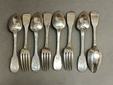 six silverplated spoons and forks lined up on a table