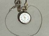 a silver pocket watch on a chain with a chain around it