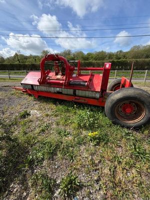 un tracteur rouge garé au milieu d'un champ, près d'une clôture