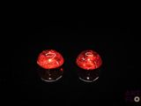 une paire de bougeoirs en verre rouge posés sur une surface noire