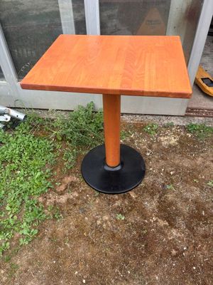 une petite table en bois posée à même le sol, avec un piètement noir