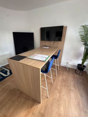 a desk with two chairs and a television in the corner