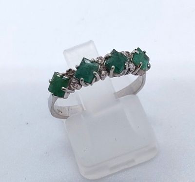 un gros plan d'une bague ornée de pierres vertes, posée sur un socle transparent