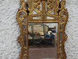 un miroir doré accroché au mur, à côté d'un sol en carrelage noir