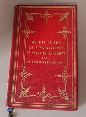 an old red book sitting on top of a white table