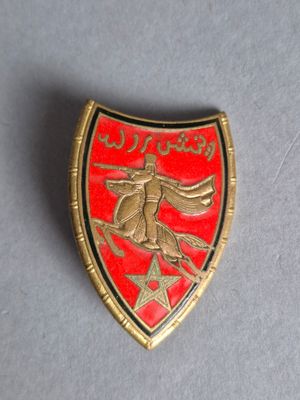 une photo d'un insigne rouge et doré sur lequel figure un oiseau