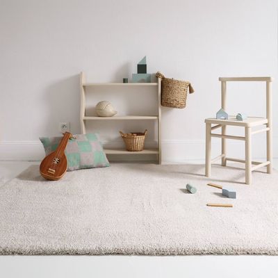 un tapis blanc posé au sol dans une pièce où se trouvent une chaise et une guitare