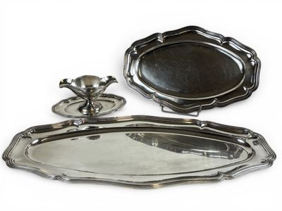 deux plateaux en argent et un bougeoir sur fond blanc