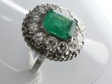 an image of a ring with a green stone surrounded by white diamonds
