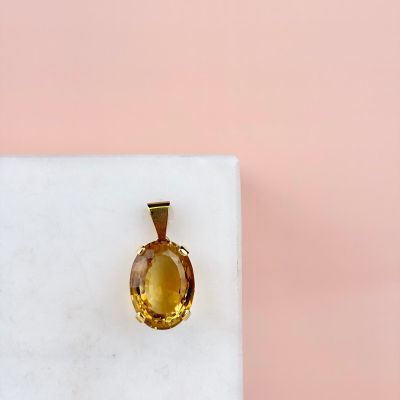 an oval citrine stone pendant on a white marble block
