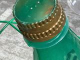 a green bottle with a gold cap sitting on a green wire