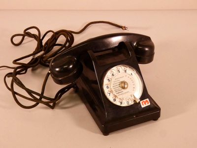un téléphone noir posé sur une surface blanche, avec un fil