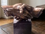 a bronze sculpture of a hand on top of a wooden table