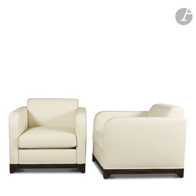 une paire de fauteuils en cuir crème avec des pieds en bois foncé