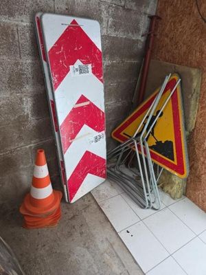 un panneau rayé de rouge et de blanc à côté d'un tas de panneaux de chantier