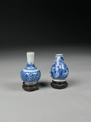 two blue and white vases sitting on top of a wooden stand