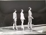 black and white photograph of three men walking on a tennis court