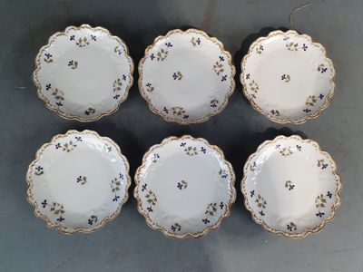 six assiettes blanches ornées de fleurs bleues, posées sur une table