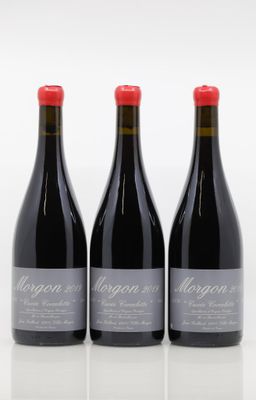 three bottles of red wine sitting on top of a white table