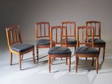 quatre chaises en bois à l'assise rembourrée sont disposées en rangée