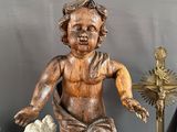 a wooden statue of a little boy holding a cross